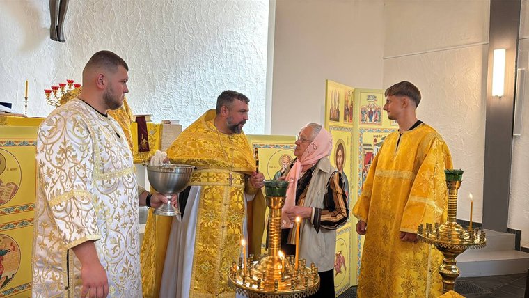 Geistliche in goldenen und weißen Gewändern am Altar, die Schale mit Weihwasser und Leuchter