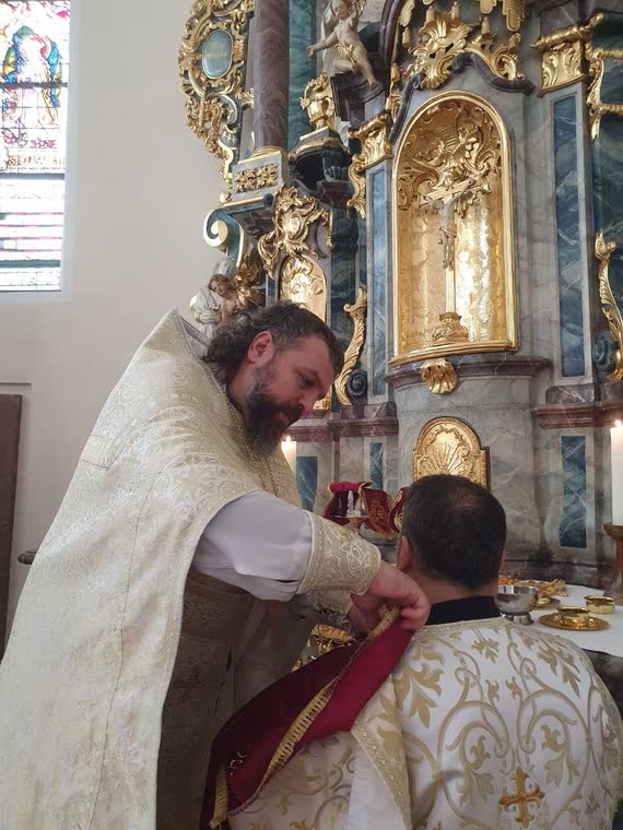 Священник поправляє облачення на іншому священникові біля вівтаря