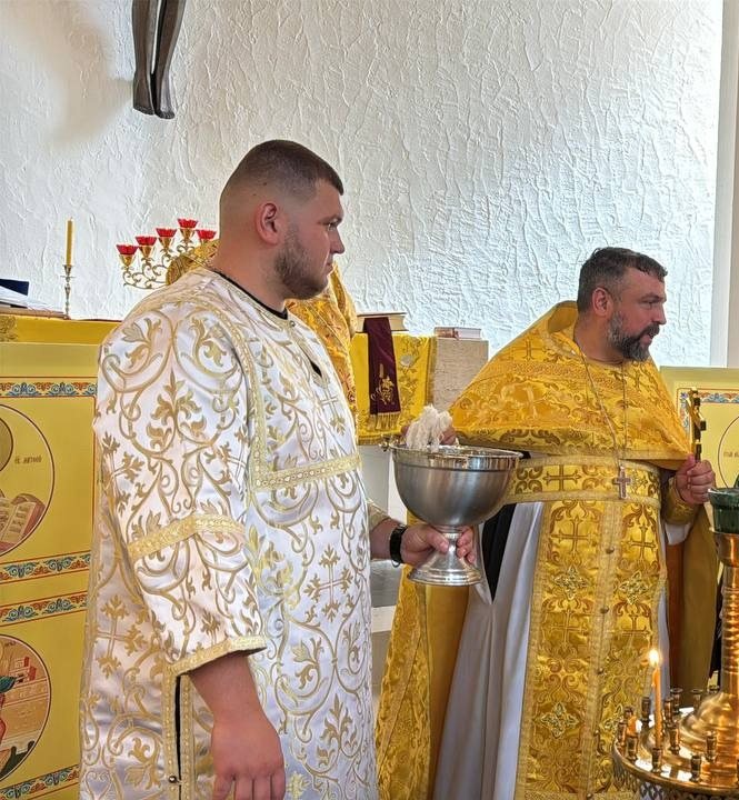 Ein Altardiener im weißen Gewand hält die silberne Schale mit Weihwasser und dem Weihwedel, daneben der Priester in goldenem Gewand